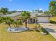 Well-manicured front yard featuring mature palm trees, landscaping, and a spacious driveway at 25313 Durango Ct, Punta Gorda, FL 33955