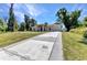 Spacious driveway leads to a charming single-story home with a well-kept lawn, mature trees, and a one-car garage at 2679 Pascal Ave, North Port, FL 34286
