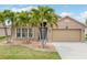 Charming home featuring a well-manicured lawn, mature palm trees, and a two-car garage at 2699 Suncoast Lakes Blvd, Punta Gorda, FL 33980