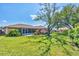 Spacious backyard with a screened lanai, lush landscaping, and a mature tree for shade at 3287 Meadow Run Cir, Venice, FL 34293