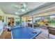 Spacious sunroom with ping pong table, dining area, and views of the landscaped backyard at 3287 Meadow Run Cir, Venice, FL 34293