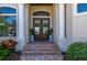 Elegant home entrance featuring double doors with glass panels, flanked by pillars and vibrant landscaping at 347 Portofino Dr, Punta Gorda, FL 33950
