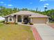 Charming single-story home featuring a beige exterior, arched entryway, well-manicured lawn, and an attached two-car garage at 3614 January Ave, North Port, FL 34288