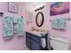 Bathroom features a blue vanity, oval mirror, flamingo-themed decor, and soft lighting at 4022 Beaver Ln # 500C, Port Charlotte, FL 33952