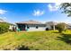 Backyard of home features green grass, a patio with a blue awning, and a grill at 5309 Shell Mound Cir, Punta Gorda, FL 33982