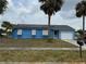 Charming single-story home featuring a vibrant blue exterior, complemented by solar panels and a well-maintained lawn at 6249 Drucker Cir, Port Charlotte, FL 33981