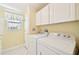 Functional laundry room with white washer and dryer, storage cabinets, and a window at 724 Blackburn Blvd, North Port, FL 34287