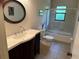 Stylish bathroom featuring a modern sink vanity, elegant mirror, and shower-tub combo with glass doors at 1022 Waterside St, Port Charlotte, FL 33952