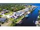 Aerial view showcases waterfront home with private dock, manicured lawn, solar panels, and canal access at 12676 Bacchus Rd, Port Charlotte, FL 33981