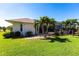 Backyard view of the home's screened in lanai, lush lawn, and tropical plants at 12676 Bacchus Rd, Port Charlotte, FL 33981