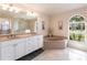 Bright bathroom featuring a large vanity, soaking tub, and a window offering natural light at 12676 Bacchus Rd, Port Charlotte, FL 33981