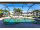 Waterfront pool with an enclosure and tropical foliage at 12676 Bacchus Rd, Port Charlotte, FL 33981