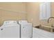 Well-lit laundry room featuring a washer, dryer, sink, and overhead shelving for optimal storage at 1352 Raspberry Dr, North Port, FL 34289