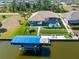 Waterfront home featuring a private boat dock, a screened pool, and lush landscaping at 15618 Aqua Cir, Port Charlotte, FL 33981