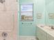 Bright bathroom featuring a tiled shower, grab bar and a vanity with light green colored walls at 15618 Aqua Cir, Port Charlotte, FL 33981