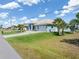 Exterior of a light blue single-Gathering home with a three-car garage and lush lawn at 15618 Aqua Cir, Port Charlotte, FL 33981