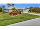 Inviting single-story home with a manicured lawn, mature palm trees, and a spacious two-car garage at 17342 Foremost Ln, Port Charlotte, FL 33948