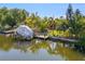 Waterfront property featuring a covered boat lift, dock and tropical landscaping at 18446 Burkholder Cir, Port Charlotte, FL 33948