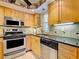 Well-equipped kitchen featuring stainless steel appliances, light wood cabinets, and granite countertops at 19505 Quesada Ave # Ee202, Port Charlotte, FL 33948