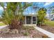 Charming house featuring mature tropical landscaping, a screened porch, and a concrete sidewalk at 212 Gulf Ave, Nokomis, FL 34275