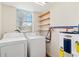 A functional laundry room includes a washer, dryer, water heater, storage shelving, and a window at 212 Gulf Ave, Nokomis, FL 34275