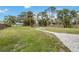 Backyard featuring a manicured lawn, mature trees, and a charming stone walkway leading to a fire pit area at 217 Palm E Ave, Nokomis, FL 34275