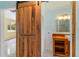 Bathroom entrance showcasing a sliding wooden door, custom vanity, and modern fixtures at 217 Palm E Ave, Nokomis, FL 34275