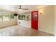 The home's living room features a ceiling fan, large windows, and a bright red entrance door at 217 Palm E Ave, Nokomis, FL 34275