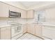 Efficient kitchen with light wood cabinets, white appliances, and tiled floors at 23482 Moreland Ave, Port Charlotte, FL 33954