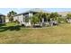 Lush backyard featuring well-maintained green grass and mature tropical trees, perfect for outdoor enjoyment at 24648 Buckingham Way, Port Charlotte, FL 33980