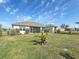 Exterior view of the house with manicured lawn, palms, and a screened-in patio at 25428 Islas Dr, Punta Gorda, FL 33955