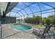 Relaxing backyard featuring a pool, spa, screened-in patio, and lounge chairs, perfect for enjoying sunny days at 303 W Grace St, Punta Gorda, FL 33950
