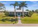 Charming home featuring a metal roof, lush landscaping, and a welcoming blue front door at 303 W Grace St, Punta Gorda, FL 33950