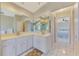Bathroom with dual sinks, a large mirror, and connecting to a bedroom with a view of the bathtub at 32 Long Meadow Ln, Rotonda West, FL 33947