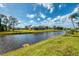 A tranquil water view from lush grassy banks featuring homes with lanais at 32 Long Meadow Ln, Rotonda West, FL 33947
