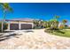 Features a three-car garage, a paver driveway, and beautiful landscaping with palm trees enhancing its curb appeal at 3657 Aruba Ct, Punta Gorda, FL 33950