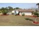 A home featuring a backyard and a patio area, complemented by a well-maintained lawn, landscaping, and palm trees at 474 Elm Nw Ave, Port Charlotte, FL 33952