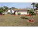A home featuring a backyard and a patio area, complemented by a well-maintained lawn, landscaping, and palm trees at 474 Elm Nw Ave, Port Charlotte, FL 33952