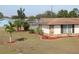 A cozy home with stone accents, complemented by a well-maintained lawn, landscaping, and palm trees at 474 Elm Nw Ave, Port Charlotte, FL 33952