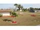 A cozy home with stone accents, complemented by a well-maintained lawn, landscaping, and palm trees at 474 Elm Nw Ave, Port Charlotte, FL 33952