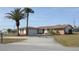 Well-manicured home featuring palm trees, a spacious driveway, and stone accents for added curb appeal at 474 Elm Nw Ave, Port Charlotte, FL 33952