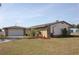 Property featuring stone accents, well-kept lawn, mature trees, and an attached two-car garage at 474 Elm Nw Ave, Port Charlotte, FL 33952