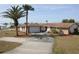 Charming single-story home featuring a stone accent, well-manicured lawn, and a circular driveway leading to an attached garage at 474 Elm Nw Ave, Port Charlotte, FL 33952