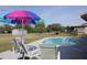 Inviting backyard oasis features a private in-ground pool and a colorful umbrella over the seating area at 474 Elm Nw Ave, Port Charlotte, FL 33952