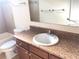 Bathroom shows single sink vanity with wood cabinets next to the toilet and tiled shower/tub at 6379 Grand Cypress Blvd, North Port, FL 34287