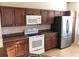Kitchen with wooden cabinets, stainless steel refrigerator, and modern white appliances including oven and microwave at 6379 Grand Cypress Blvd, North Port, FL 34287