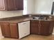 Kitchen featuring stainless steel sink, white dishwasher, and wood cabinets at 6379 Grand Cypress Blvd, North Port, FL 34287