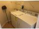 Bright laundry room includes a white washer and dryer, wire rack, and a wash sink for added convenience at 6379 Grand Cypress Blvd, North Port, FL 34287