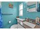 Bathroom featuring textured blue walls, a gray countertop sink and a window for natural light at 103 Curtis Ne Ter, Port Charlotte, FL 33952