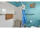 Bright bathroom with white tiled shower, vibrant blue accent wall and colorful shower curtain at 103 Curtis Ne Ter, Port Charlotte, FL 33952